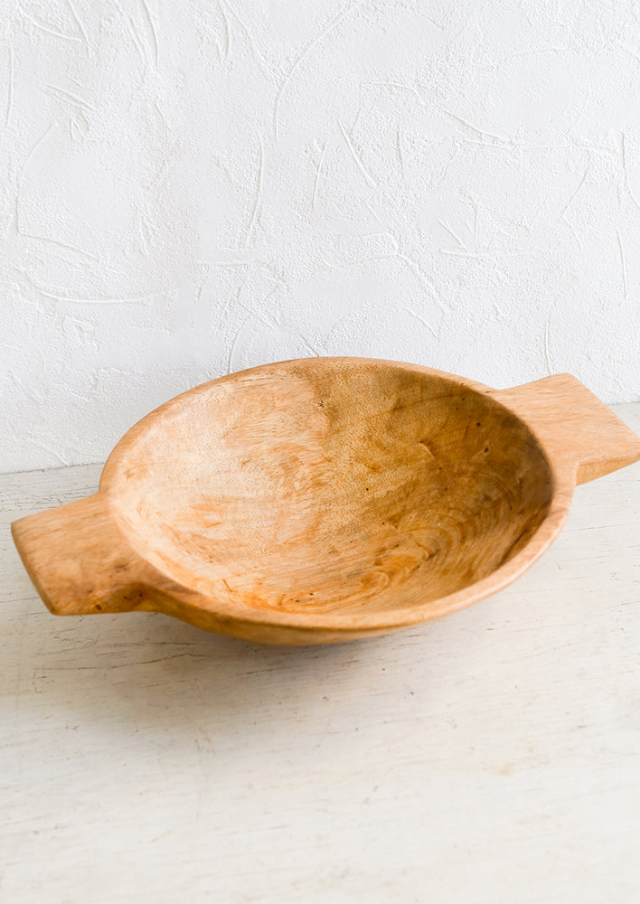 A round wooden serving bowl with side tabs.