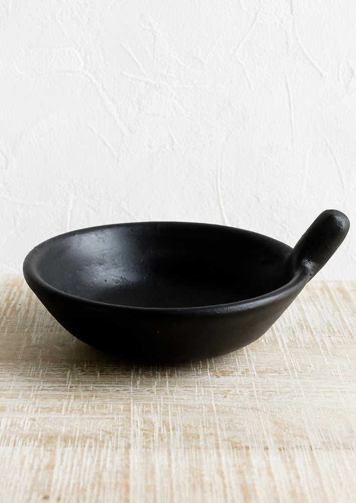 1: A round black terracotta bowl with tab handle.