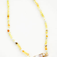 1: Beaded necklace with round gemstone beads in variegated lemon yellow, asymmetrically shaped grey pearl pendant at front and center