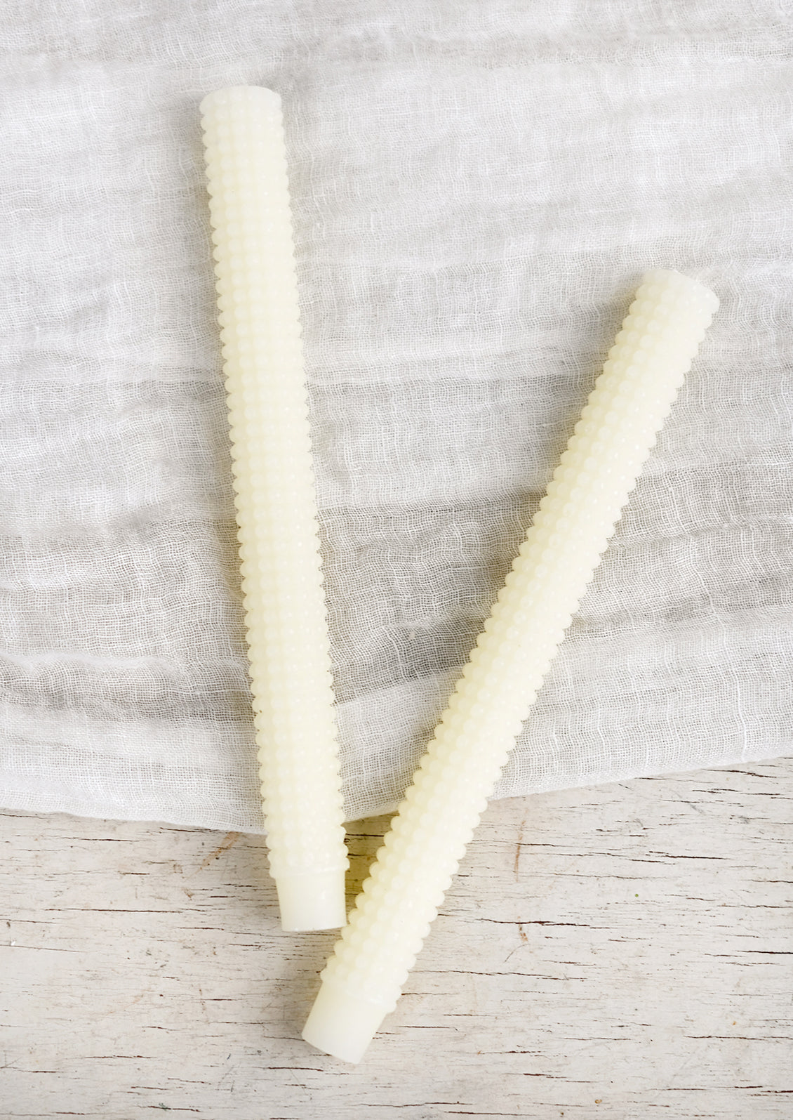 A pair of hobnail textured taper candles in ivory.