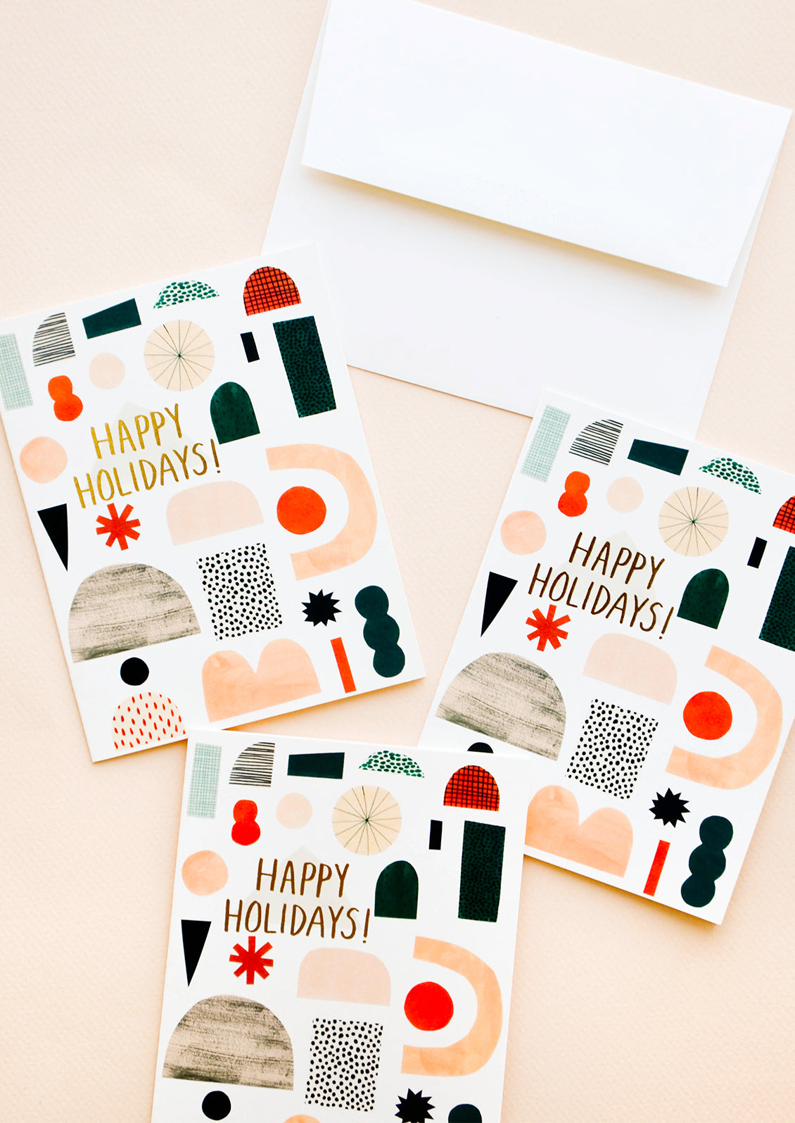 Three greeting cards with illustrated shapes and "Happy Holidays" written in gold foil.