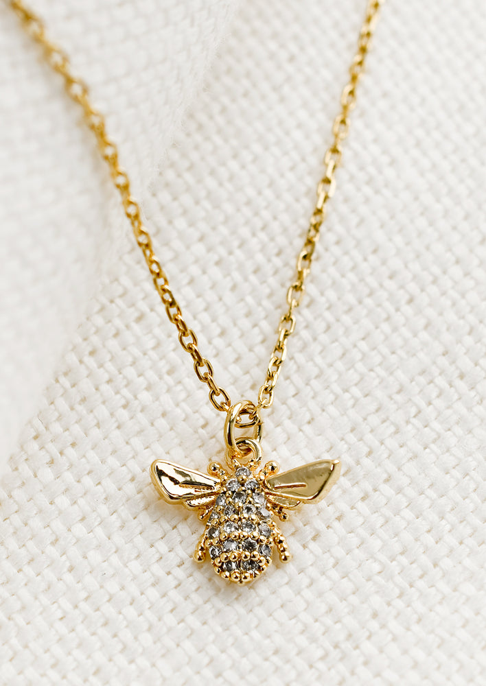 A gold necklace with crystal bee charm.