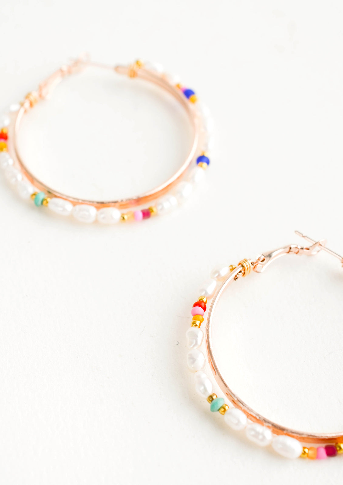 Round hoop earrings with beaded outer layer of pearls and colored glass seed beads and rosegold inner hoop