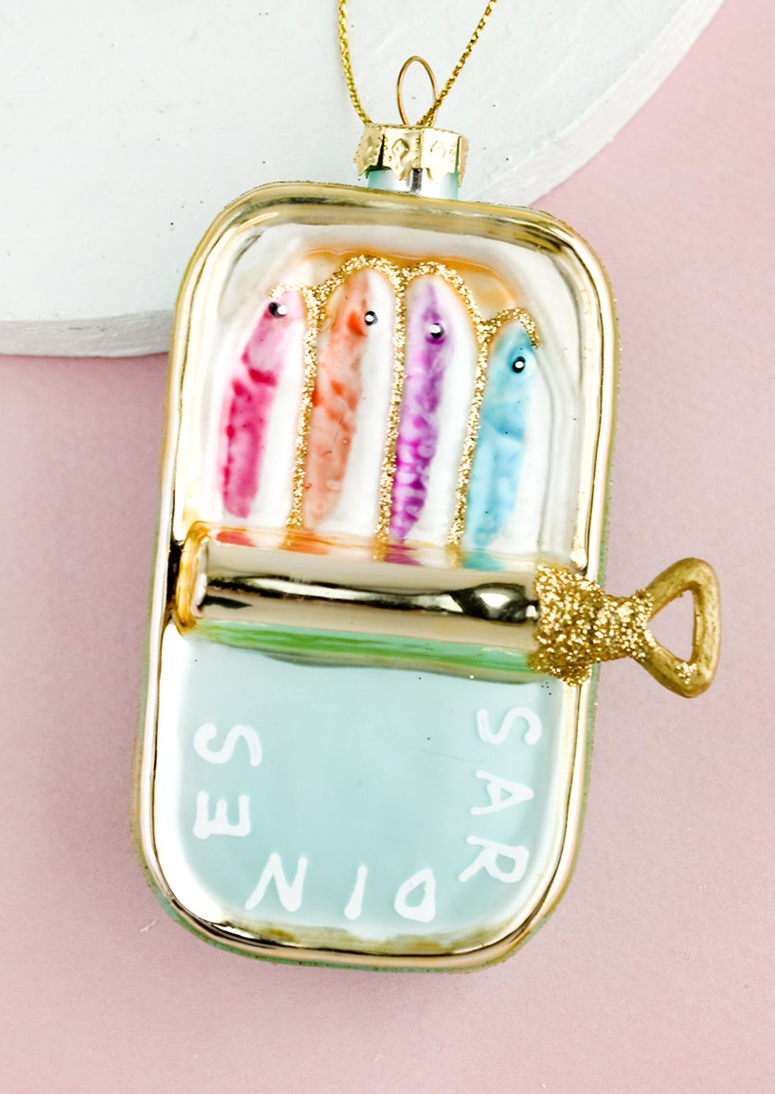 A holiday ornament of colorful sardines in a gold glass "tin".