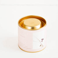 5: A candle in lidded brass tin with a pale pink paper label.
