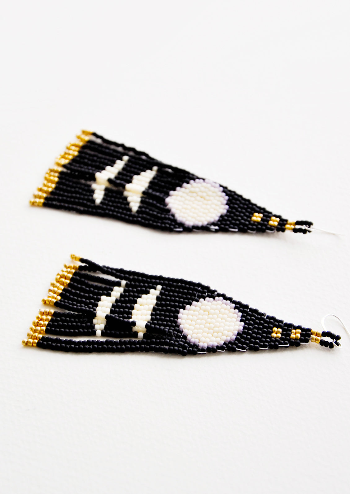 Dangling earrings with black and white geometric beaded shapes and black and gold beaded fringe.