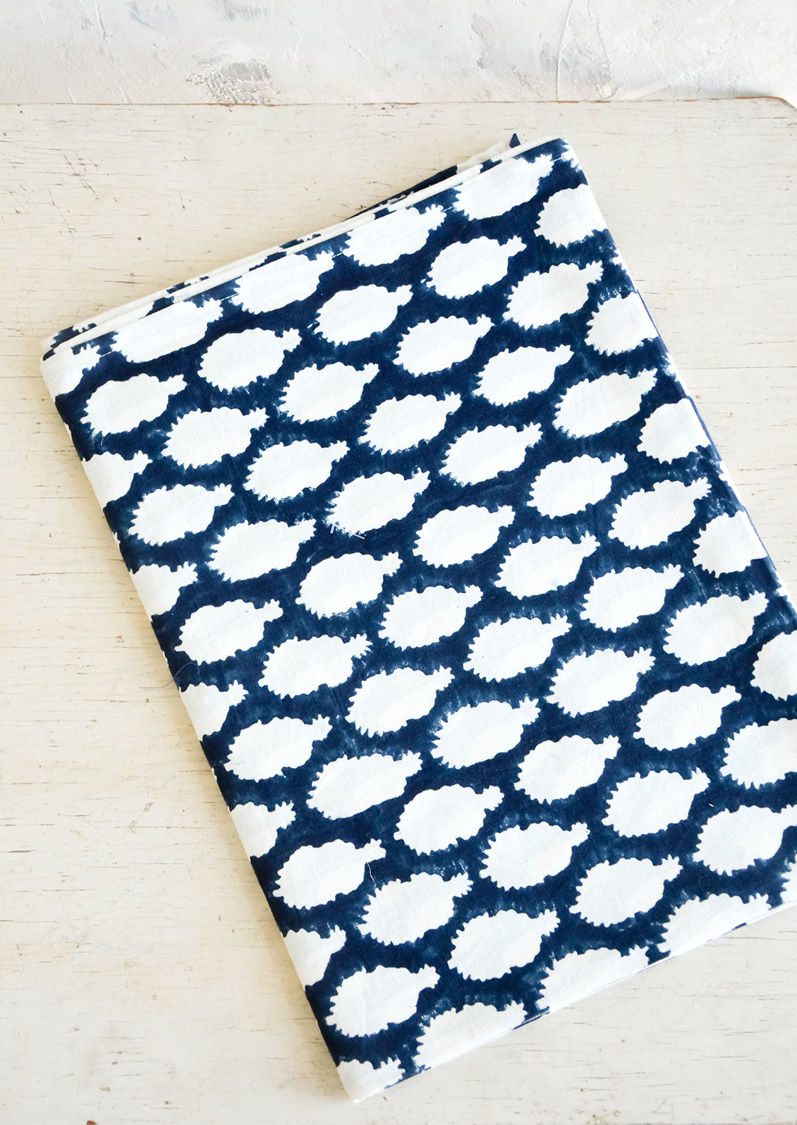 Indigo and white batik tablecloth folded on a rustic table