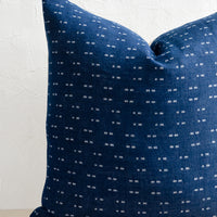 1: A square throw pillow with indigo background and white woven dash pattern.