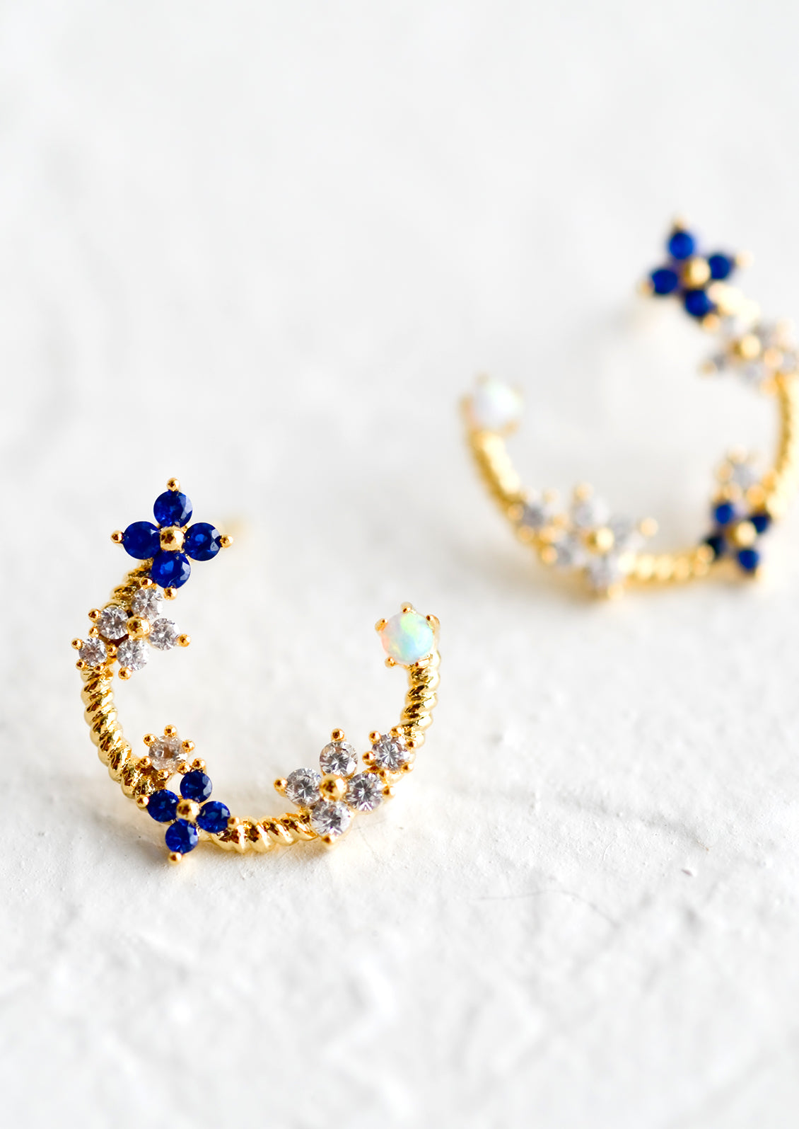 Gold hoop stud earrings with floral crystal detailing.