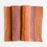 2: A terracotta linen napkin with block printed stripe design.