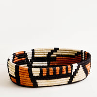 Black Multi: Oval shaped shallow bread basket made from woven natural grass in black and terracotta geometric print