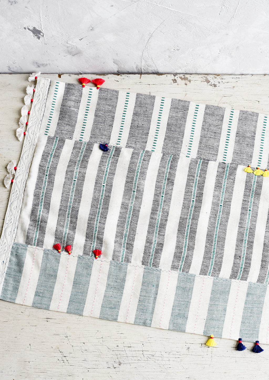 2: A madras stripe placemat in multicolor with tassel detail.