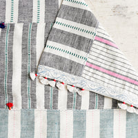 1: A madras stripe placemat in multicolor with tassel detail.