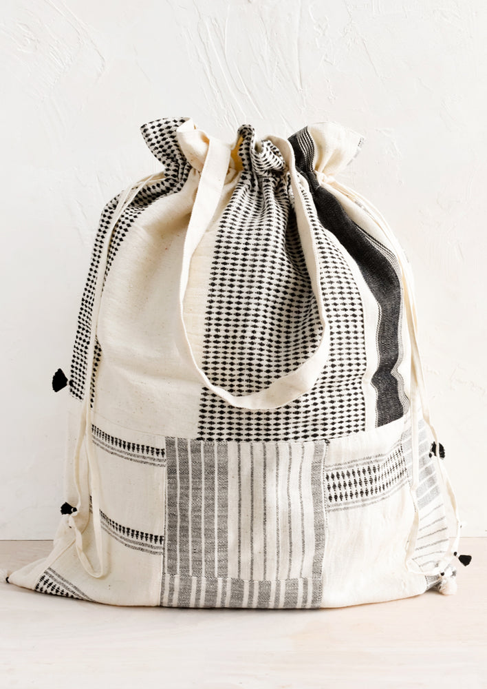 1: A black and white patchwork drawstring tote.