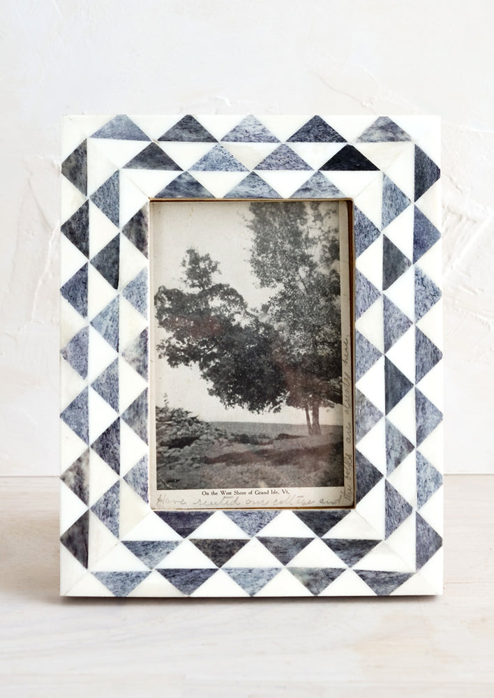 A bone picture frame with grey and white triangle print border.