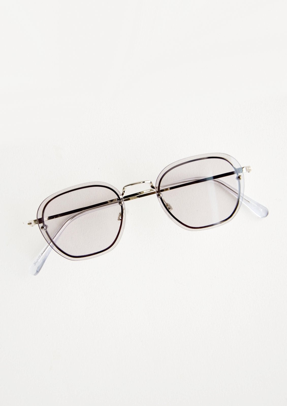 Sunglasses with grey tinted plastic lenses and a metal frame behind the lens