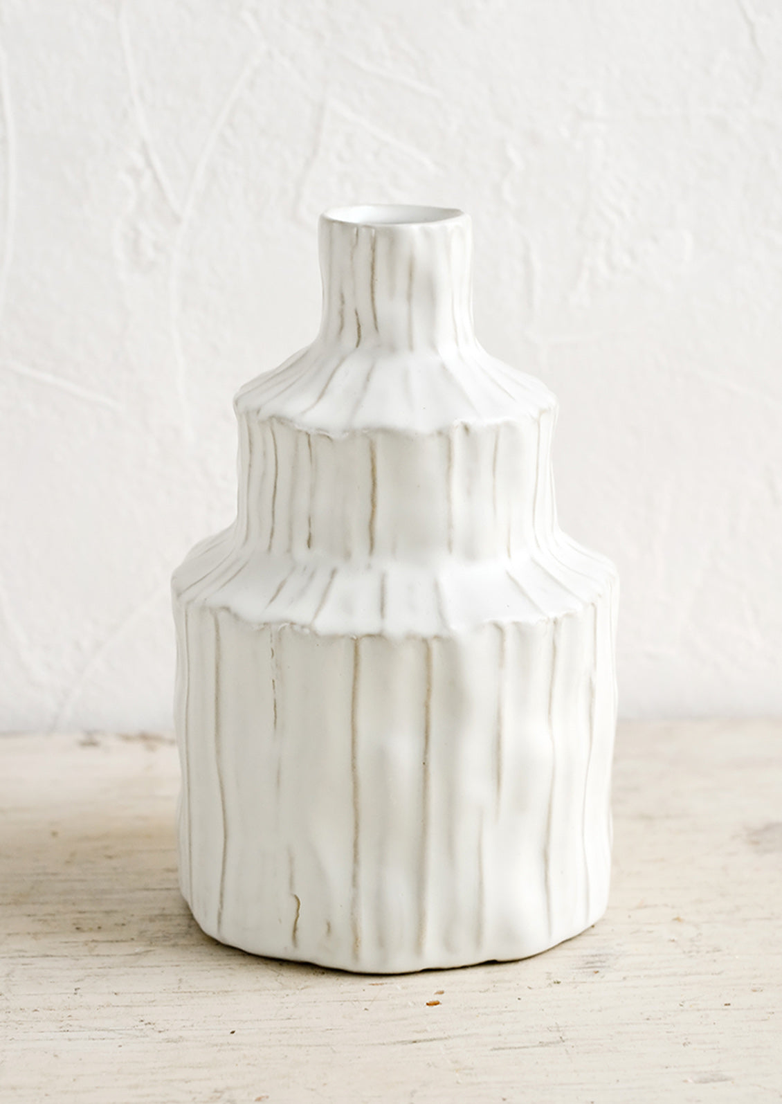 A textured white vase in an asymmetrical shape.