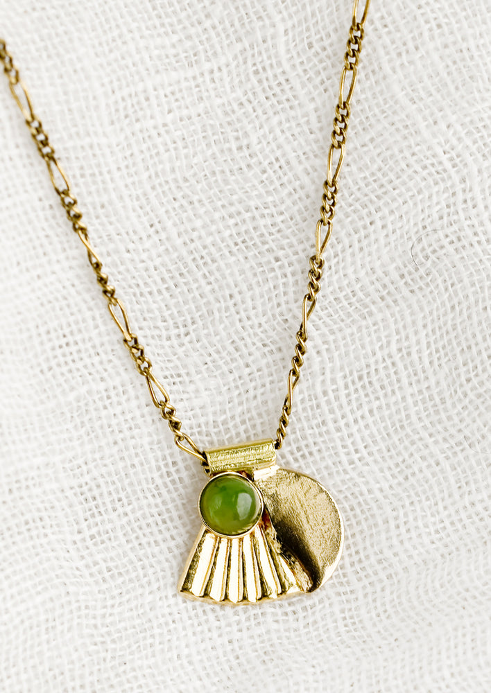 A neckace with art-deco style charm and jade bezel detail.
