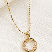 Clear: A gold necklace with circular pendant with clear inner stones.