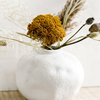 3: A white ceramic vase with dried flowers.