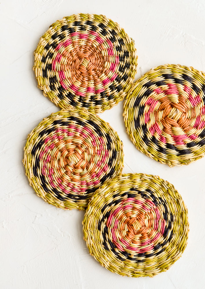 1: Four round coasters woven in natural grass with colorful design.