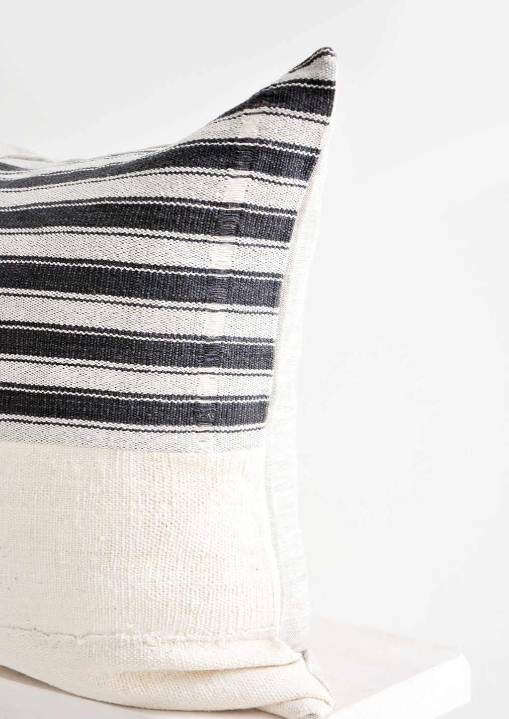 2: Square throw pillow with white and black striped top half and plain mudcloth bottom half