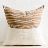 2: A throw pillow with top half in brown & ivory striped fabric and bottom half in natural mudcloth.