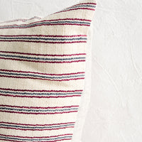 5: A throw pillow with top half in ivory, red and blue striped fabric and natural linen back.