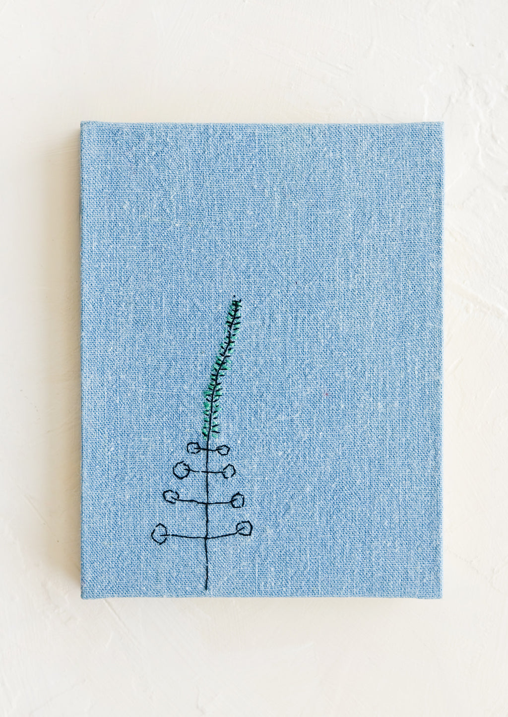 Light Indigo: A blue cloth covered journal with botanical embroidery detail.