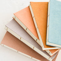 2: Five cloth-covered notebooks with hand bound pages in naturally dyed hues.