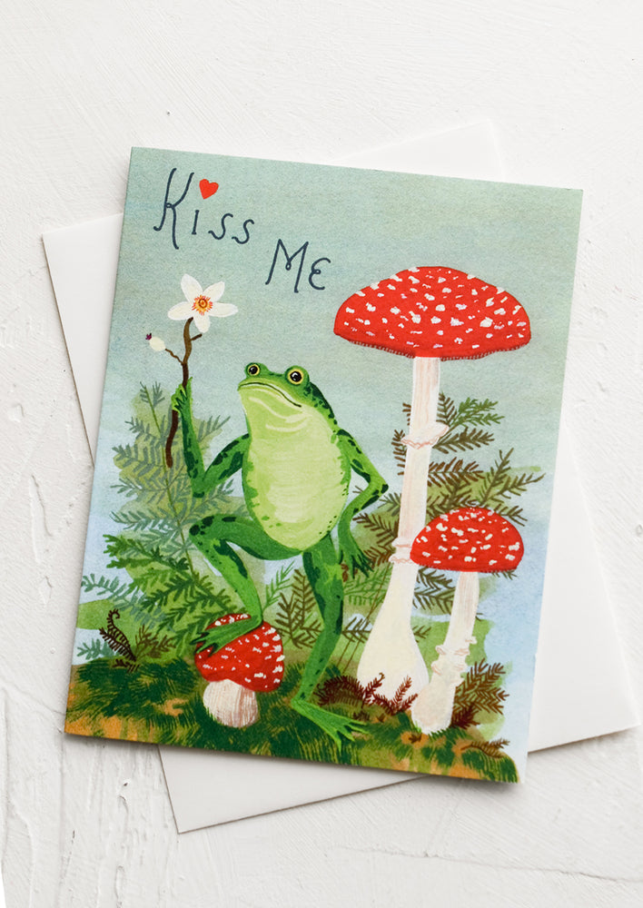 1: A greeting card with illustration of frog standing on toadstools, text reads "Kiss me".