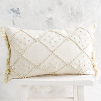 1: A natural cotton lumbar pillow with knotted design in diamond shape.