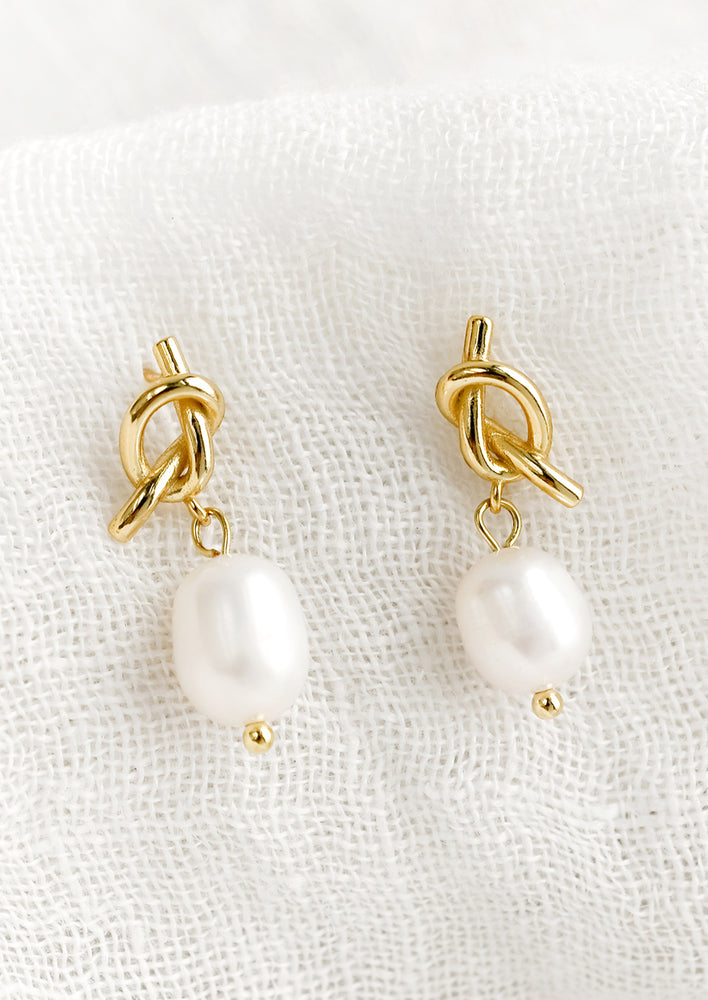 1: A pair of pearl earrings with knot shaped post in gold.
