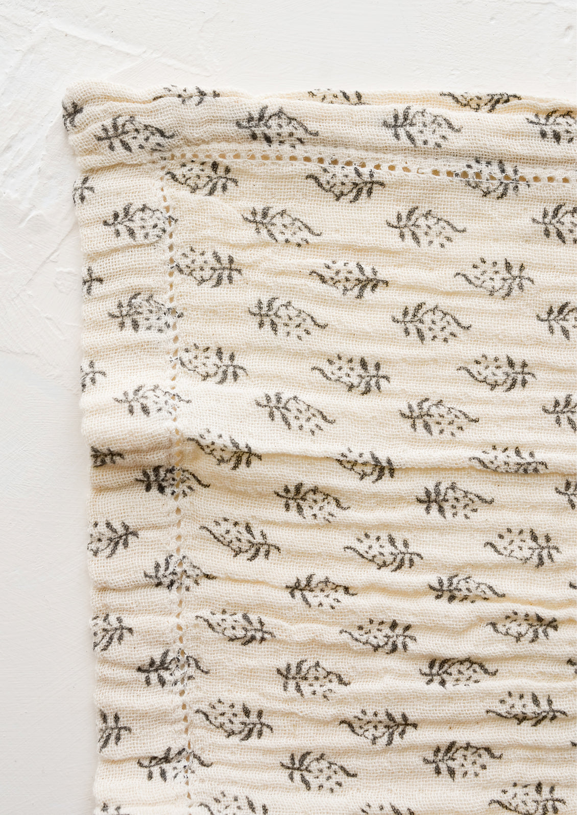 A dark grey floral motif on natural cotton gauze with hemstitch detail.