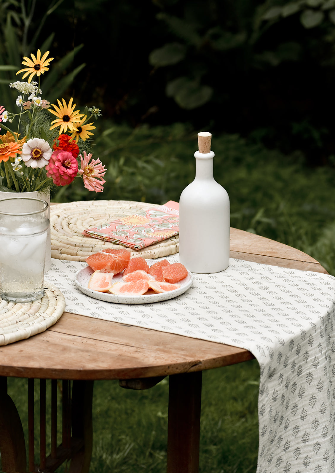 An outdoor table setting with grapefruit and flowers.