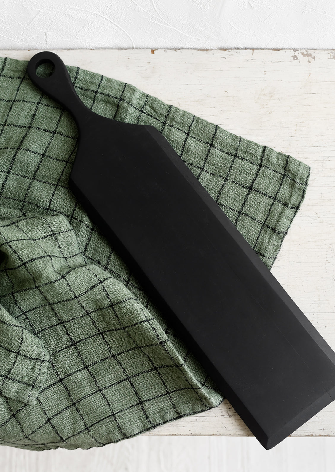 A woven tea towel in forest green with black grid pattern.