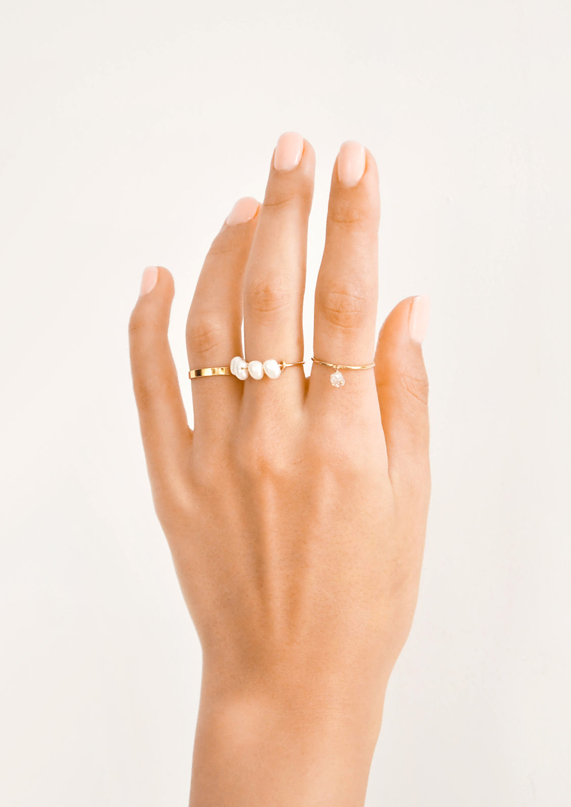 Hand modeling assorted gold and pearl rings