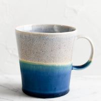 Periwinkle / Blue: A ceramic coffee mug with handle in speckled periwinkle and matte ocean blue glaze.