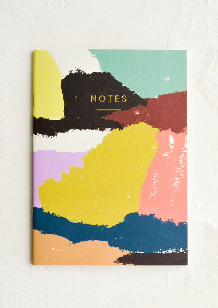 A notebook with abstract patterned cover and "NOTES" in gold letters.
