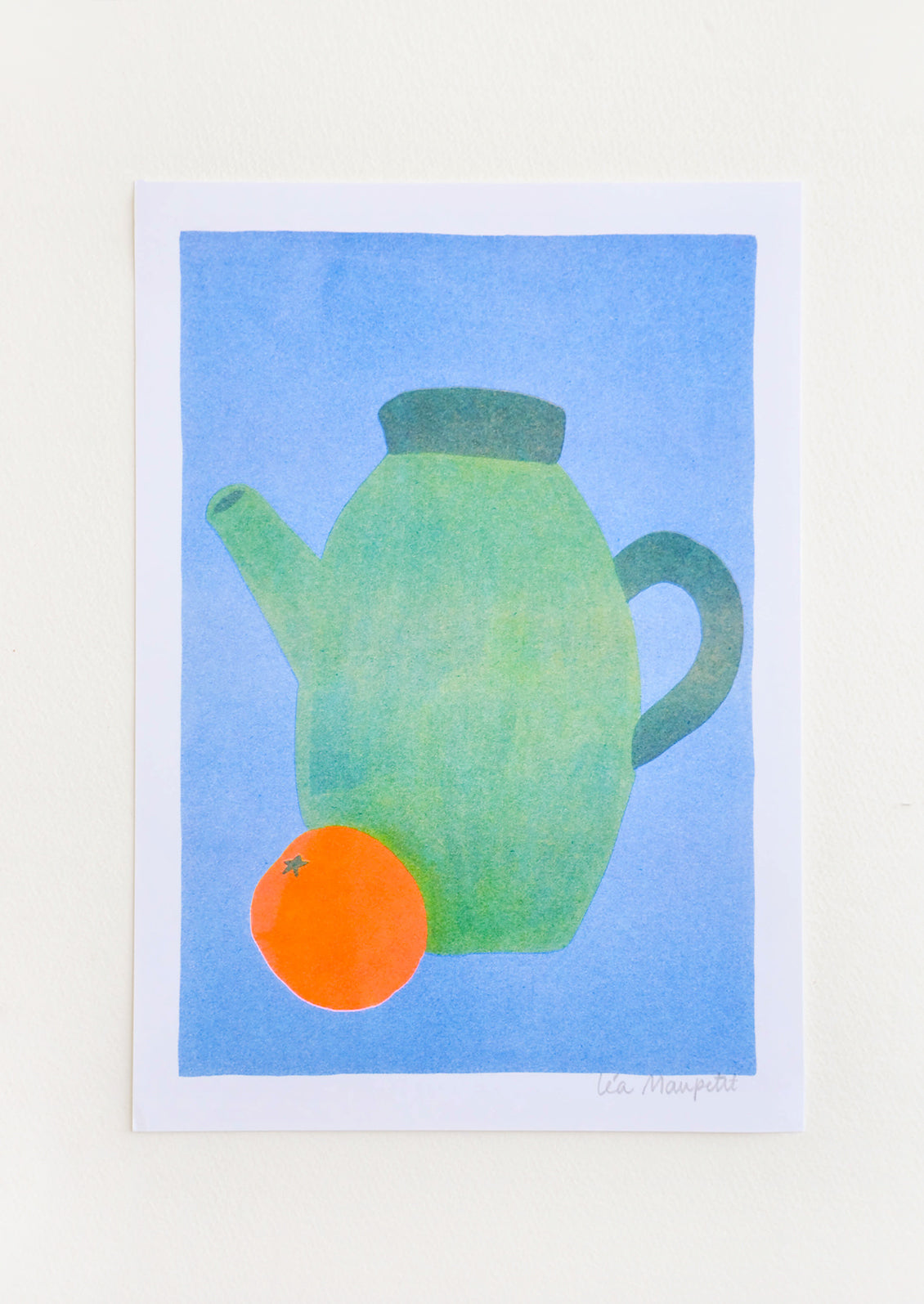 Still life of a green teapot and an orange against a bright blue background.