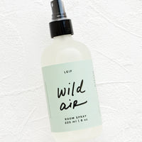 Wild Air: Frosted glass spray bottle with black cap and green label with black text