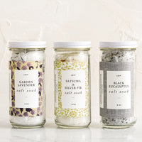 3: Three glass jars with decorative labels containing bath salt soaks.