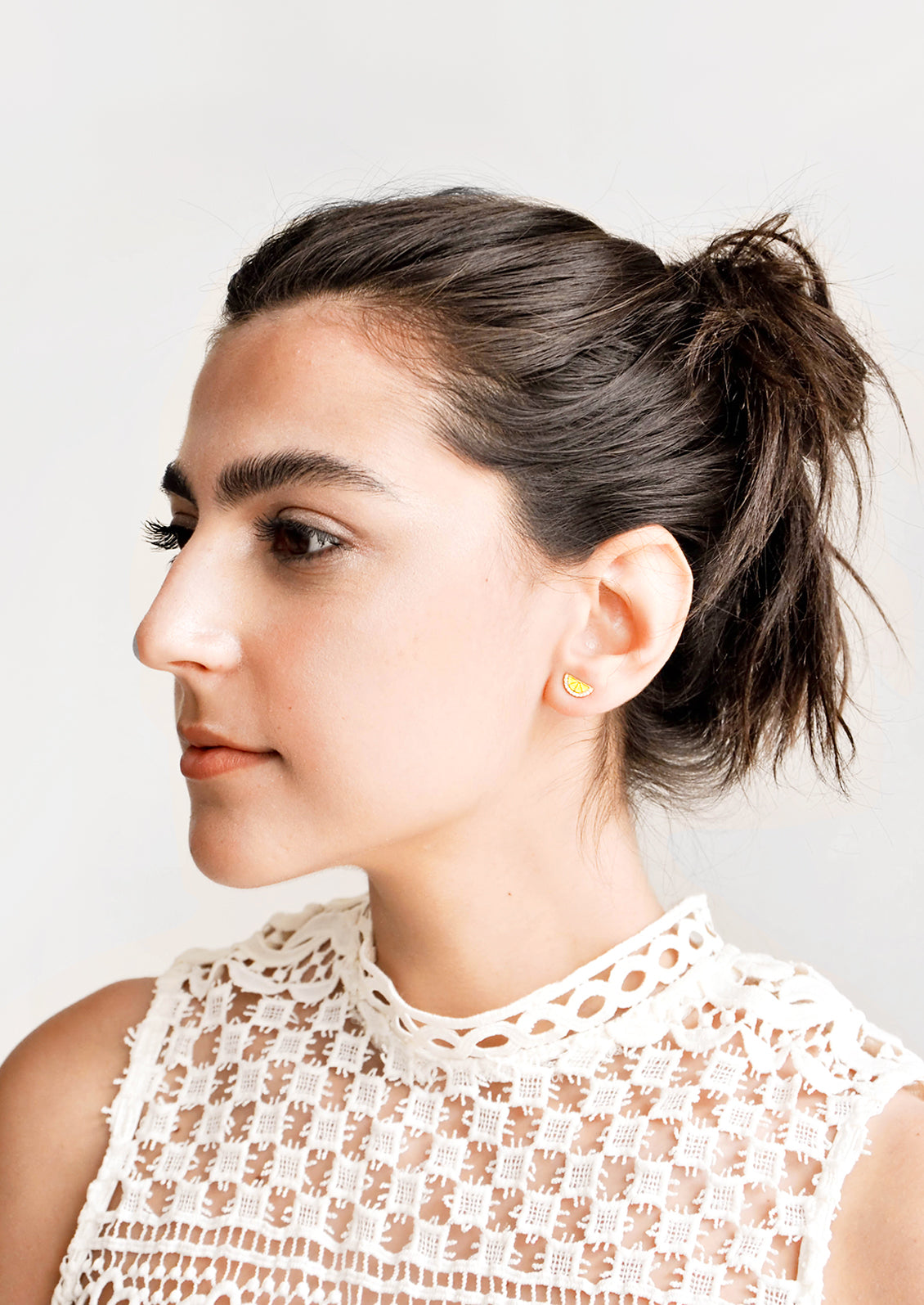 Brunette model wearing lemon shaped stud earrings.
