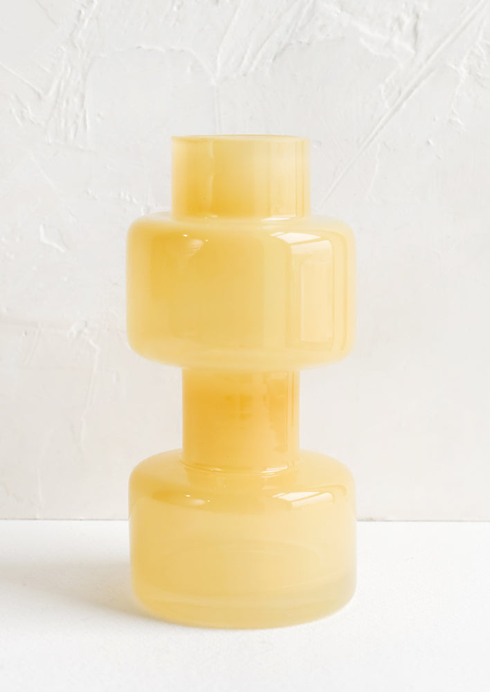 A glass vase in translucent yellow hue with barbell-like shape.