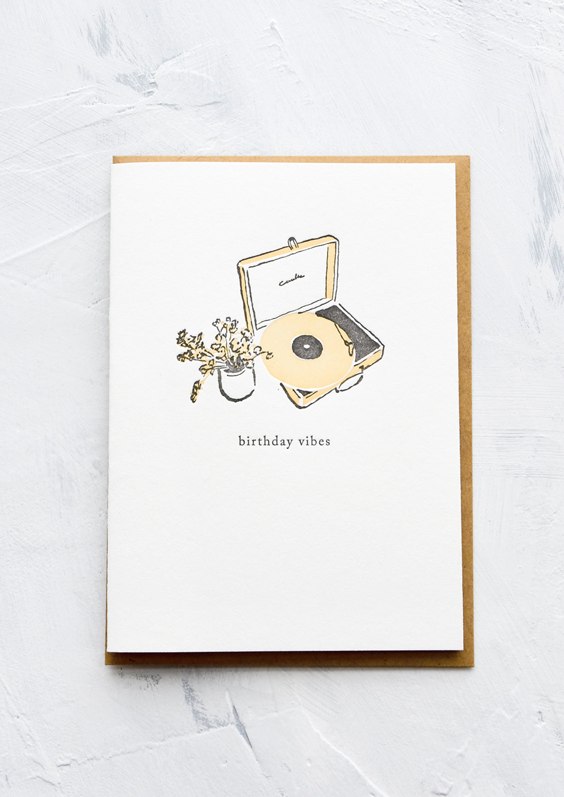 A letterpress printed greeting card with an image of a record player and flowers, text below image reads "birthday vibes".