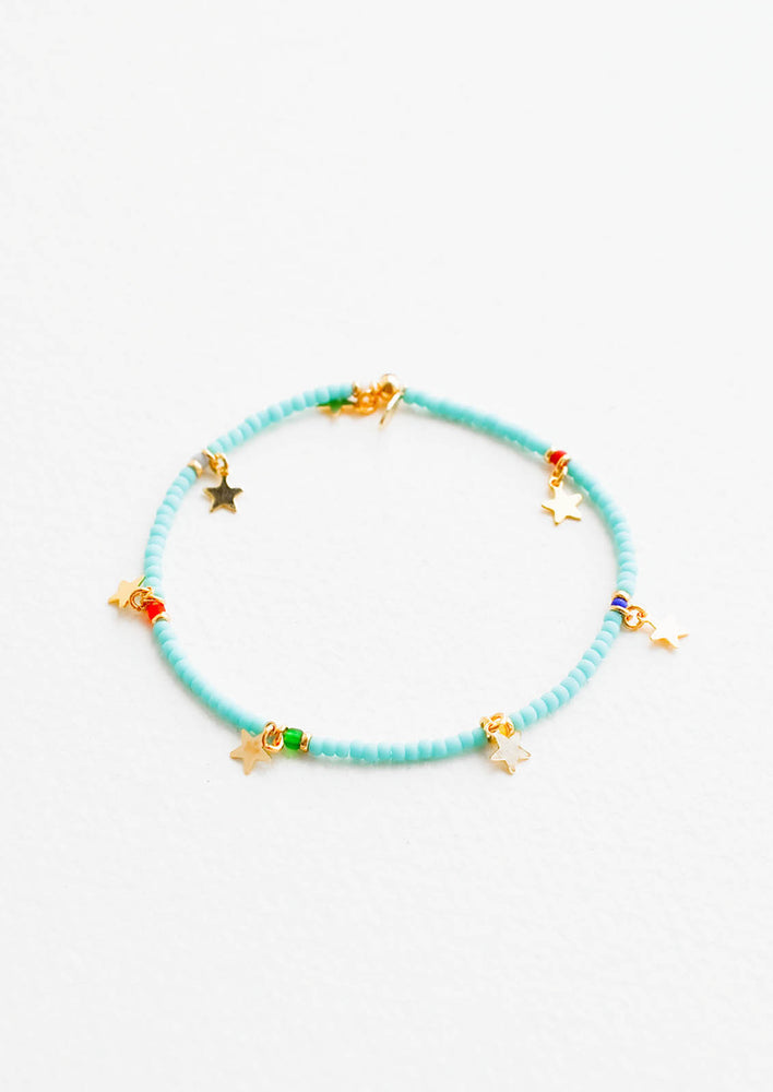 Turquoise glass beaded bracelet interspersed with gold star charm and multicolored accent beads, on an elastic cord.
