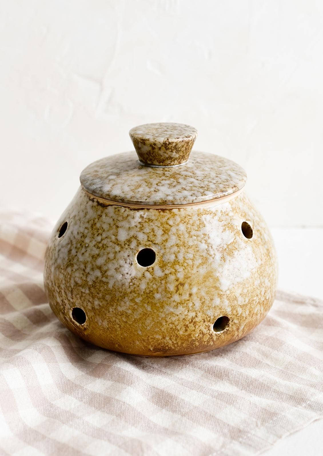 A brown ceramic garlic keeper with lid.