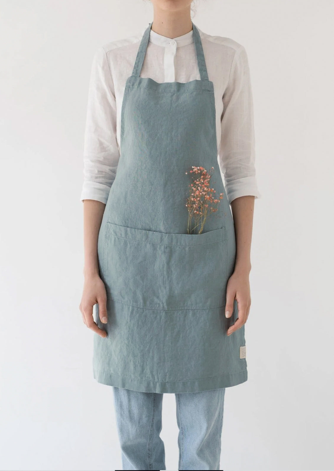A women wearing a linen apron in lake blue color.