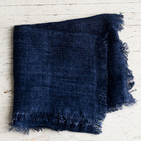Indigo: A folded navy blue linen napkin with frayed edges.