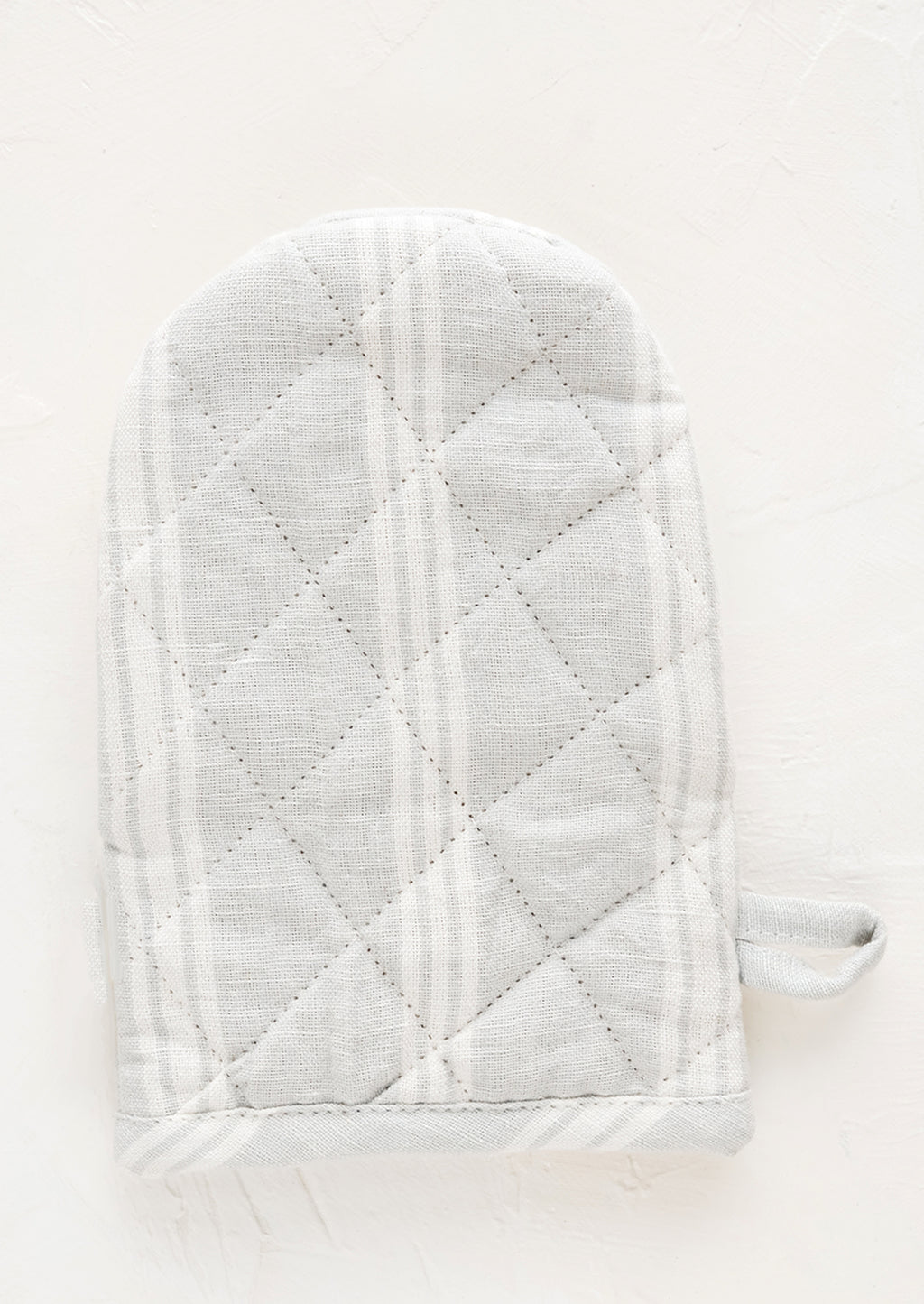 Cloud / White: A quilted oven mitt made from light grey and white striped linen.